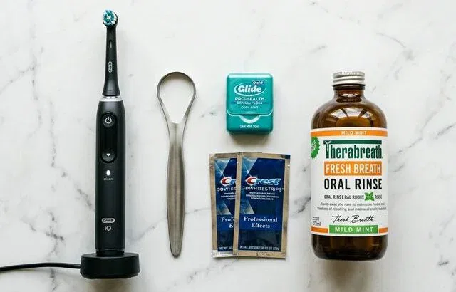 Men's oral care essentials flatlay: toothbrush, floss, tongue scraper, mouthwash