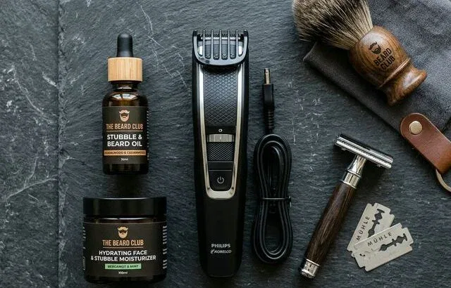 Men's stubble grooming products flat lay on dark stone