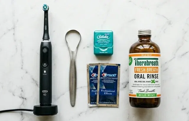 Men's oral care essentials flatlay: toothbrush, floss, tongue scraper, mouthwash